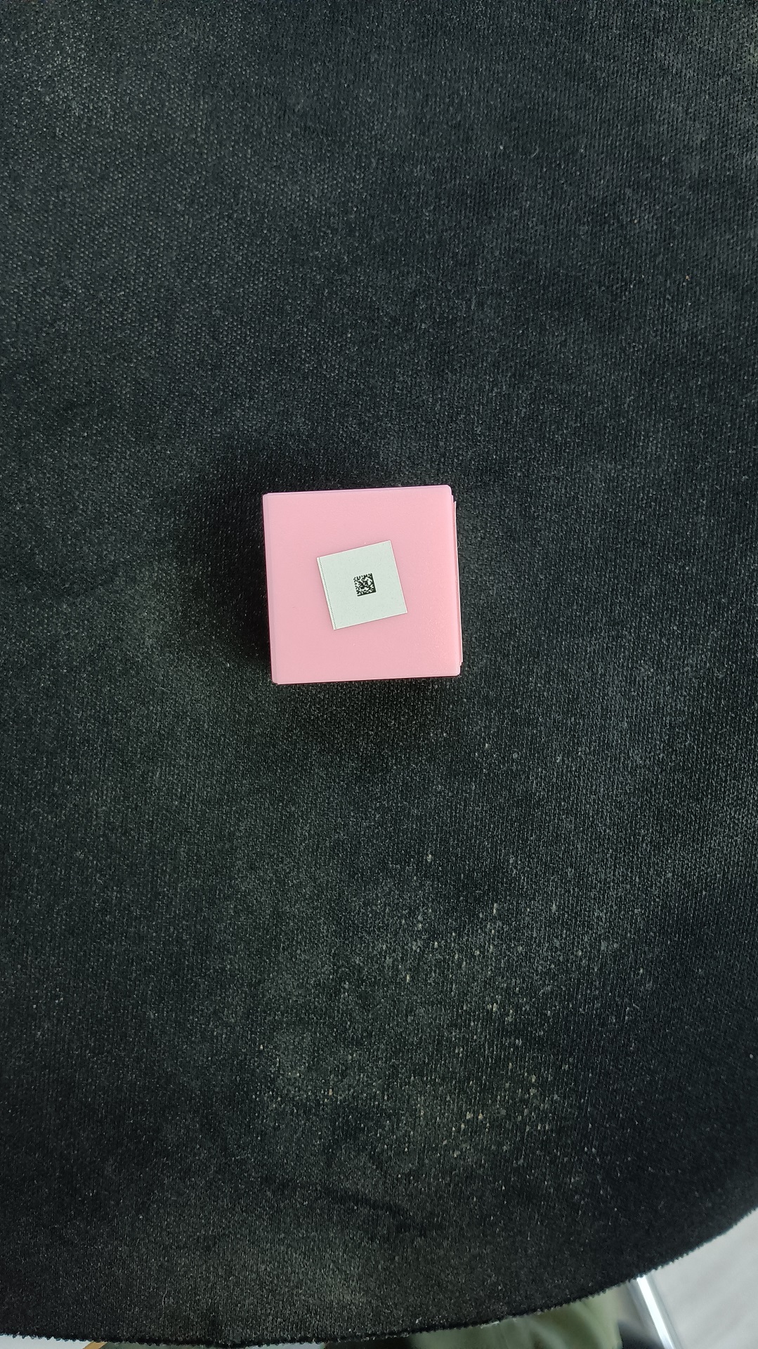 Original example image with a tiny DataMatrix code on a pink object against a dark textured background
